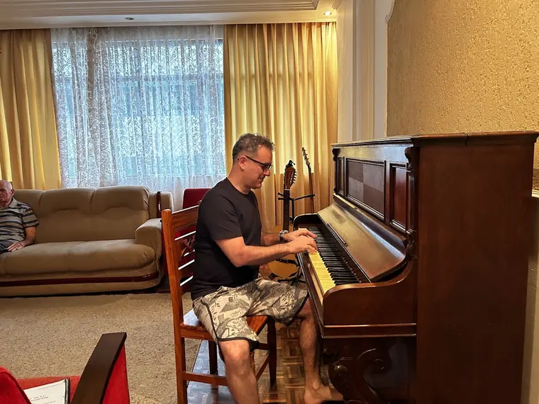Fabricio Costa tocando piano, de costas para a sala